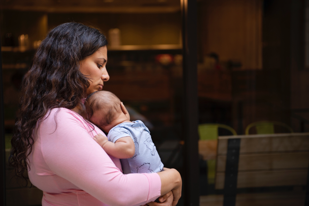 Sad woman cradling newborn baby.