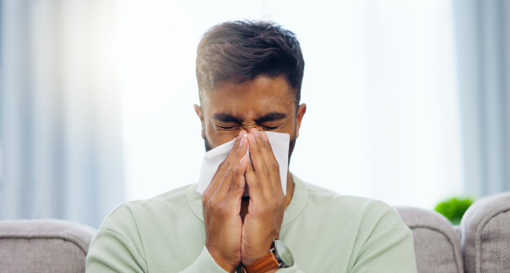 A man sneezing from allergies.